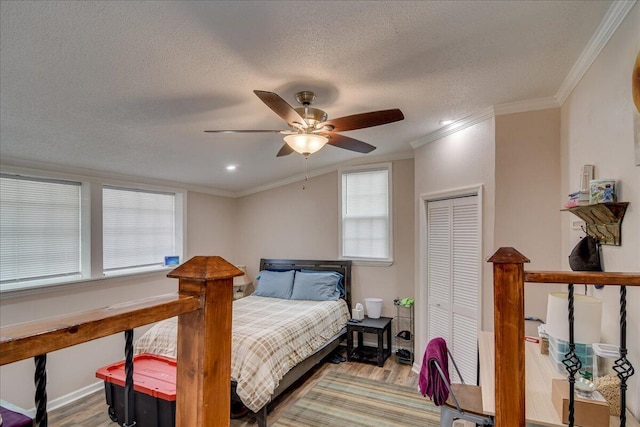 bedroom featuring ceiling fan, ornamental molding, a textured ceiling, wood-type flooring, and a closet