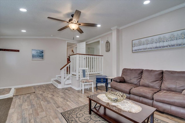 living room featuring crown molding, light hardwood / wood-style flooring, ceiling fan, and a textured ceiling