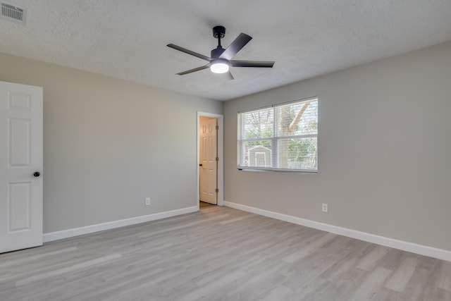 empty room with a textured ceiling, light wood-style floors, visible vents, and baseboards