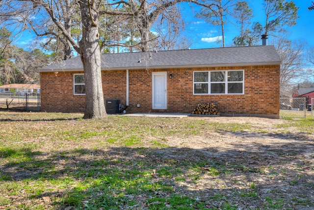 rear view of house with brick siding, fence, and a lawn