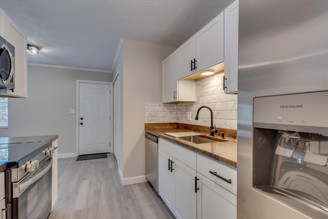 kitchen with white cabinets, appliances with stainless steel finishes, decorative backsplash, and a sink