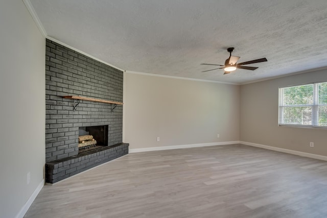 unfurnished living room featuring a textured ceiling, a brick fireplace, wood finished floors, and crown molding