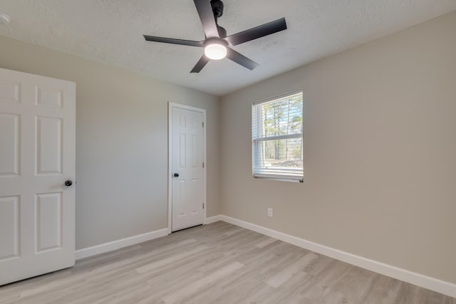 unfurnished bedroom with light wood finished floors, a ceiling fan, baseboards, and a textured ceiling