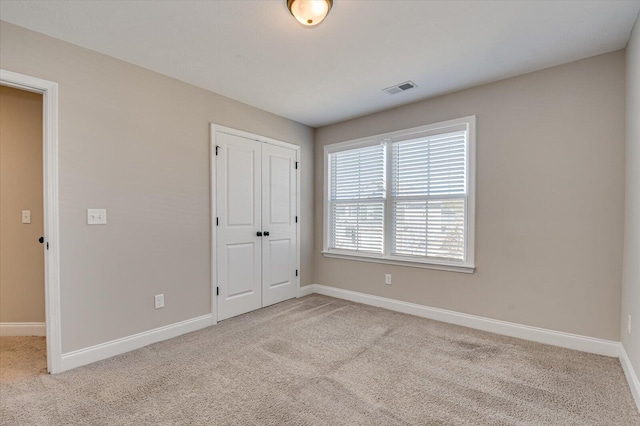 unfurnished bedroom with a closet and light colored carpet