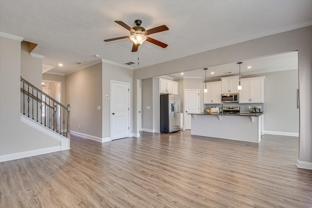 unfurnished living room with ceiling fan, ornamental molding, and light wood-type flooring