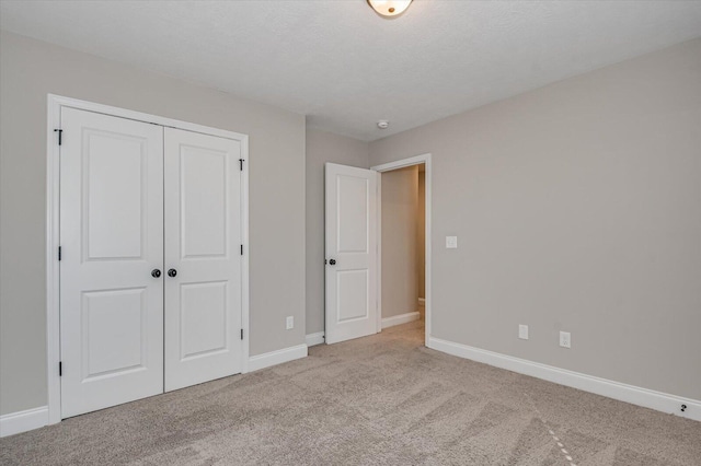 unfurnished bedroom with light colored carpet and a closet