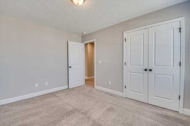 unfurnished bedroom with light colored carpet and a closet