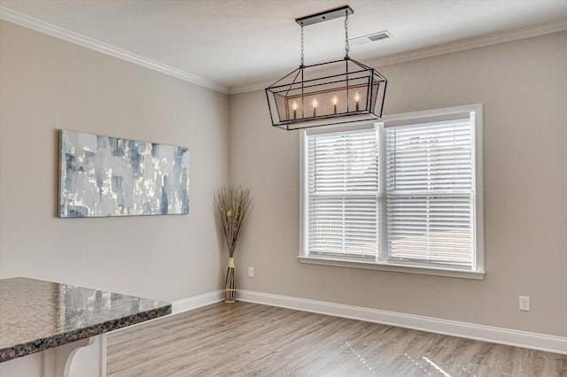 unfurnished dining area with an inviting chandelier, ornamental molding, and light hardwood / wood-style flooring