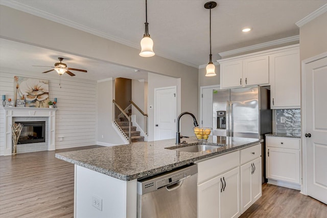 kitchen with white cabinets, sink, stainless steel appliances, and a center island with sink