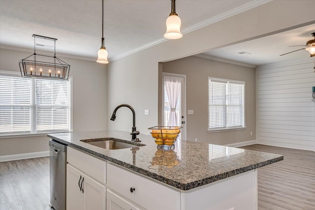 kitchen with dark stone countertops, a center island with sink, stainless steel dishwasher, sink, and white cabinets