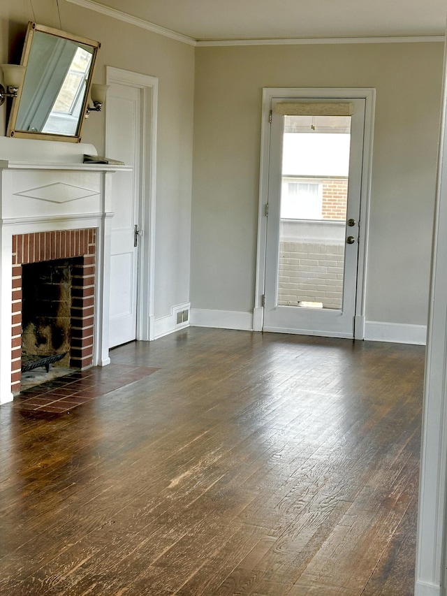 unfurnished living room with baseboards, visible vents, dark wood finished floors, ornamental molding, and a brick fireplace