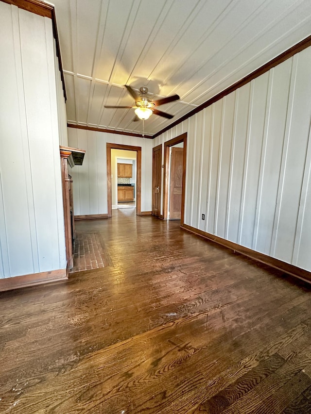 unfurnished living room featuring dark wood-style floors, ceiling fan, baseboards, and crown molding