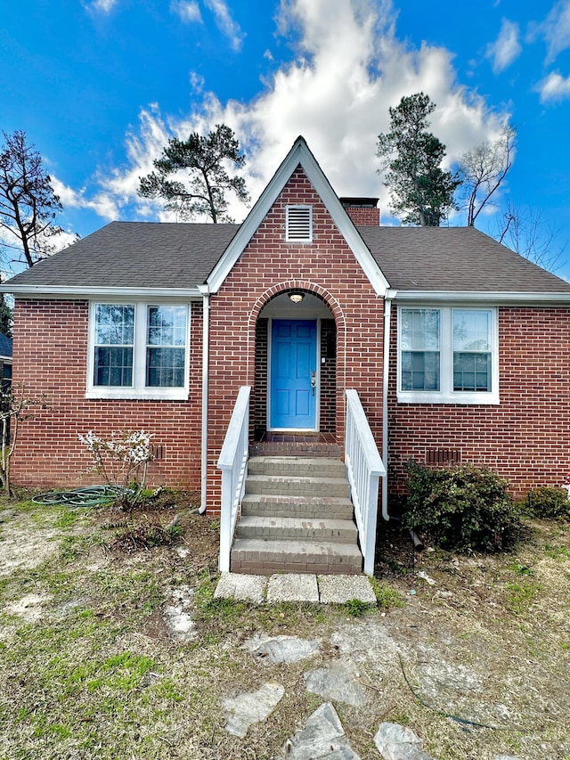 view of front of home with a shingled roof and brick siding