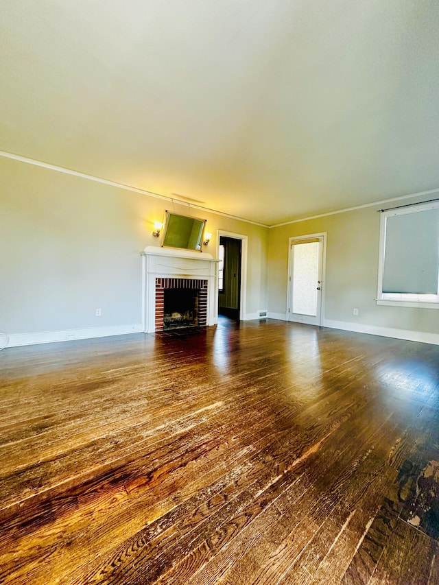 unfurnished living room featuring crown molding, dark wood-type flooring, a fireplace, and baseboards