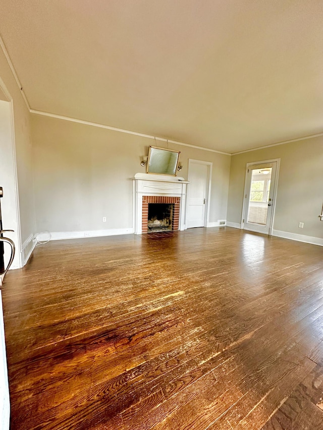 unfurnished living room with visible vents, baseboards, ornamental molding, dark wood-type flooring, and a brick fireplace