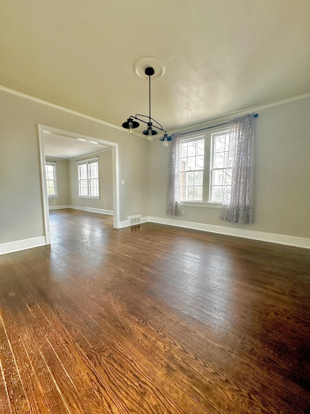 unfurnished dining area featuring dark wood-type flooring, visible vents, crown molding, and baseboards