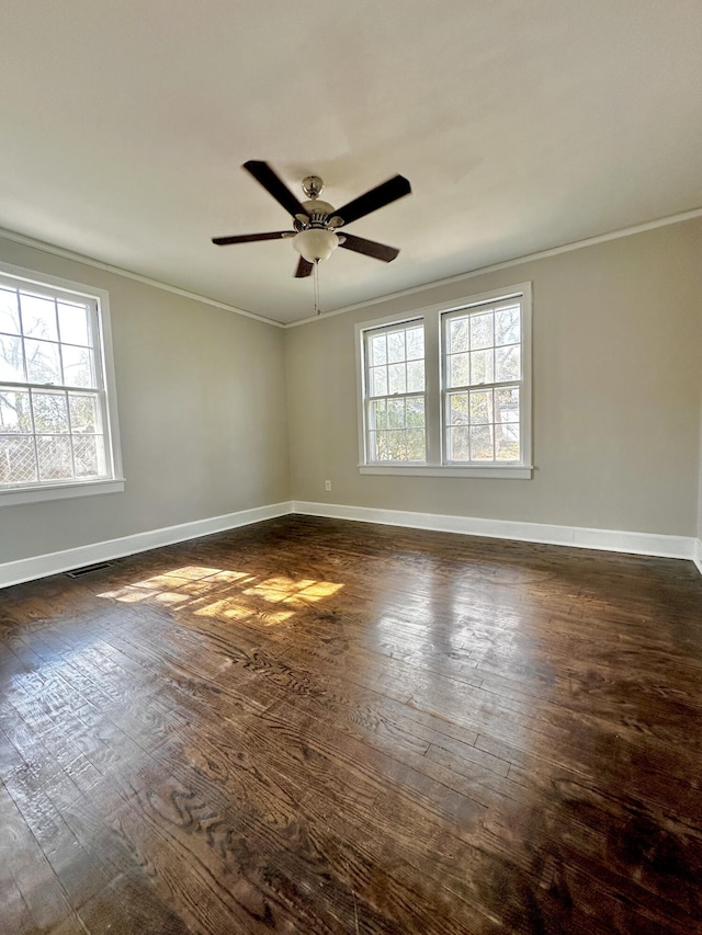 unfurnished room featuring ornamental molding, dark wood-style flooring, a healthy amount of sunlight, and baseboards