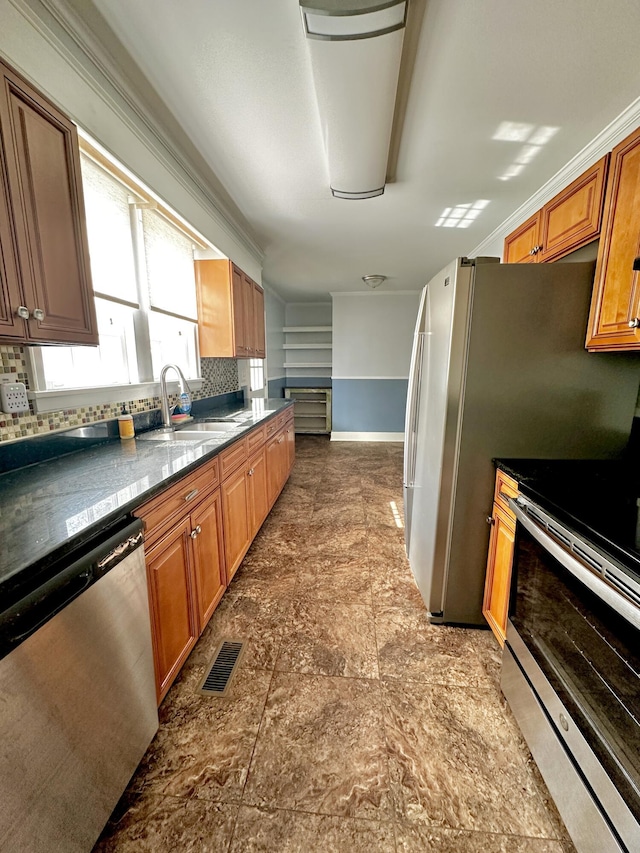 kitchen featuring stainless steel appliances, dark countertops, visible vents, and a sink