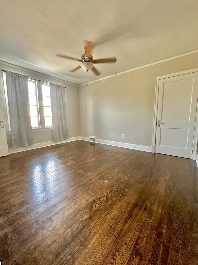 spare room with dark wood-style floors, crown molding, ceiling fan, and baseboards