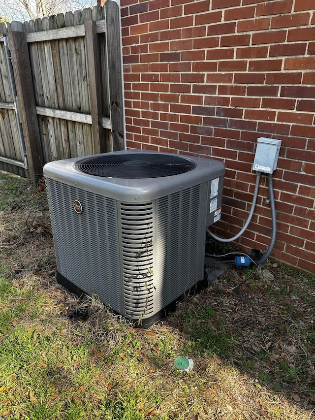 details featuring central AC, brick siding, and fence