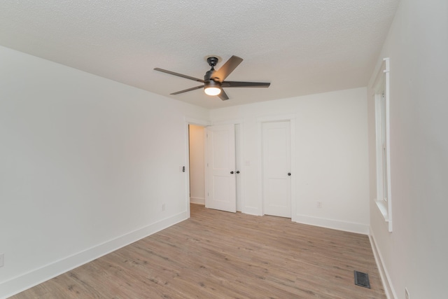 unfurnished bedroom featuring ceiling fan, a textured ceiling, and light wood-type flooring