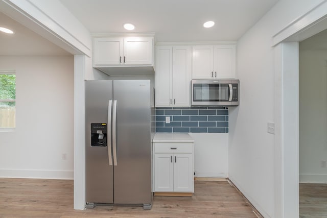 kitchen with decorative backsplash, white cabinetry, stainless steel appliances, and light hardwood / wood-style flooring