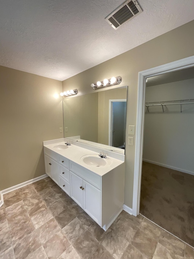 930 Hunting Horn Way, Evans, GA 30809 - bathroom featuring a textured ceiling, double vanity, baseboards, and a spacious closet