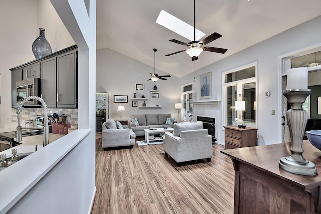 123 Tara Dr, Mccormick, SC 29835 - living area with a fireplace, ceiling fan, light wood finished floors, high vaulted ceiling, and a skylight