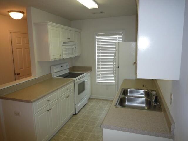 7423 Exuma Dr, Augusta, GA 30909 - kitchen with a sink, a peninsula, white appliances, light countertops, and white cabinets