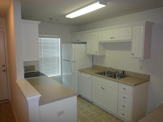 7423 Exuma Dr, Augusta, GA 30909 - kitchen with a peninsula, a sink, white cabinetry, white appliances, and light countertops