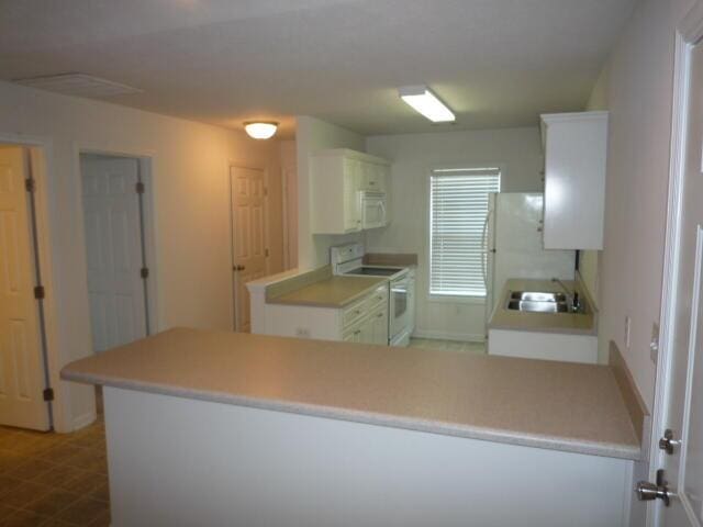 7423 Exuma Dr, Augusta, GA 30909 - kitchen with white appliances, a sink, a peninsula, light countertops, and white cabinets