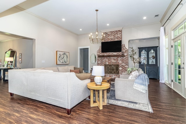 living area featuring a wealth of natural light, a notable chandelier, a fireplace, and wood finished floors