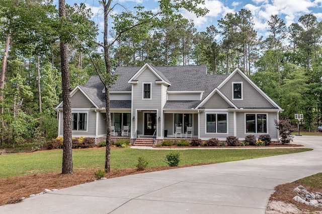 craftsman-style house with covered porch, a shingled roof, and a front yard