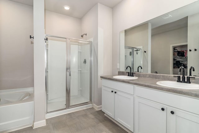 full bath featuring a sink, double vanity, a stall shower, and a bath