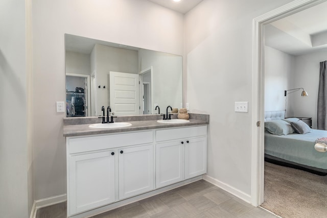 ensuite bathroom featuring baseboards, a sink, ensuite bathroom, and double vanity