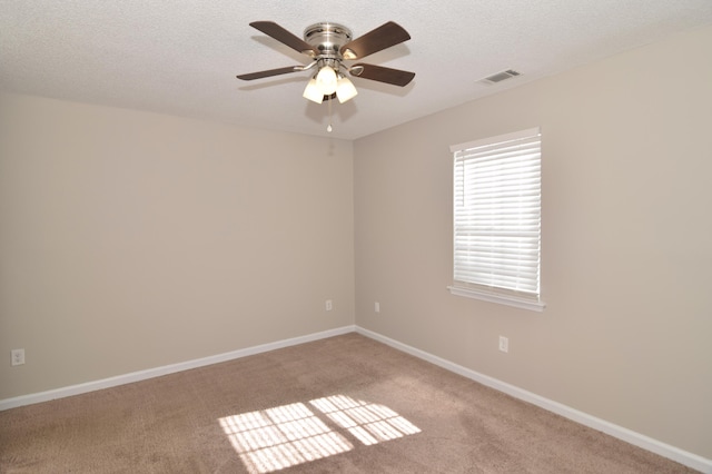 unfurnished room featuring light colored carpet, visible vents, ceiling fan, a textured ceiling, and baseboards