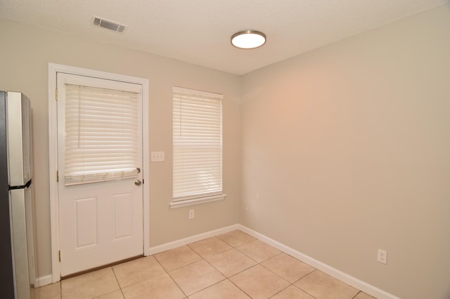 doorway to outside with visible vents, a textured ceiling, baseboards, and light tile patterned floors