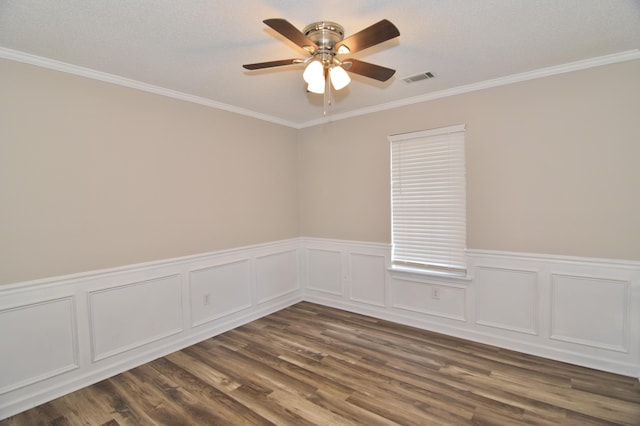 spare room with dark wood-type flooring, visible vents, ornamental molding, and a ceiling fan