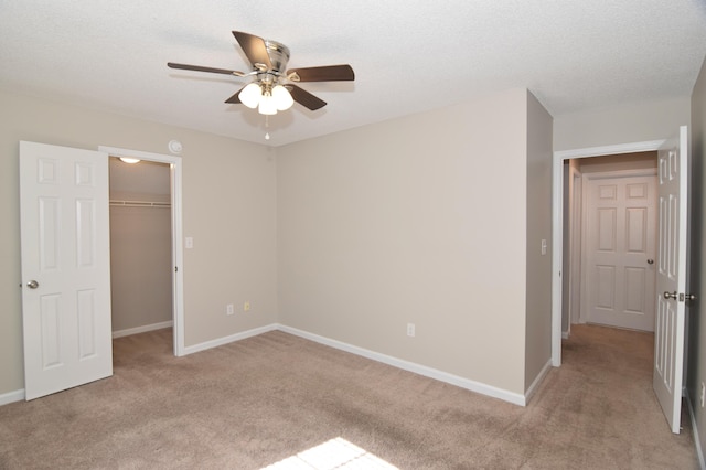 unfurnished bedroom with light carpet, a closet, a walk in closet, and baseboards