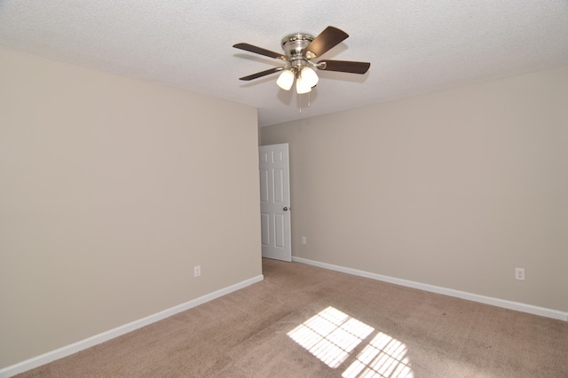 empty room featuring light carpet, ceiling fan, baseboards, and a textured ceiling