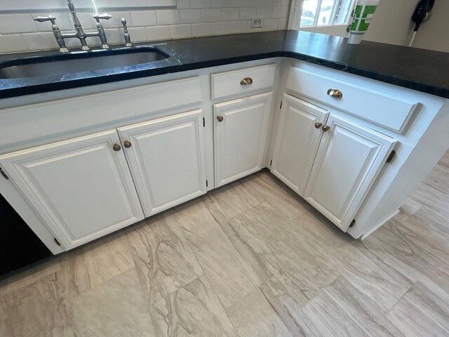 2210 Glendale Rd, Augusta, GA 30904 - kitchen featuring dark countertops, tasteful backsplash, white cabinets, and a sink