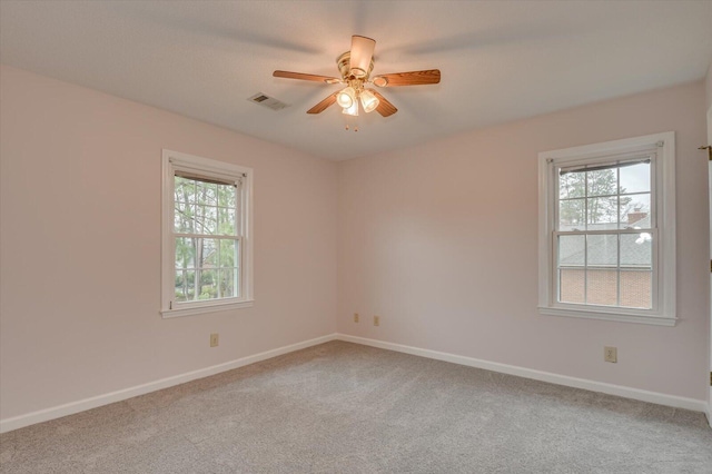 unfurnished room with plenty of natural light, carpet, visible vents, and baseboards