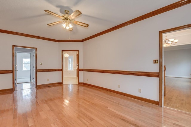 spare room with crown molding, light wood-style floors, and baseboards