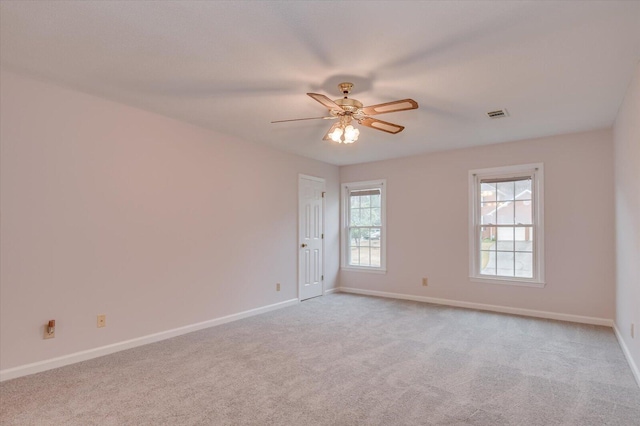 empty room with ceiling fan, baseboards, visible vents, and light carpet