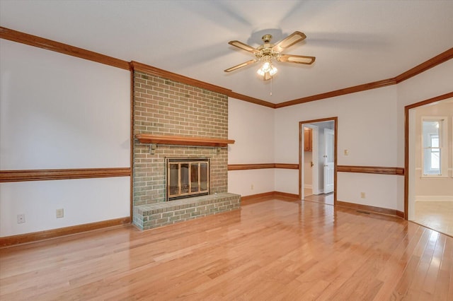 unfurnished living room with a brick fireplace, crown molding, baseboards, and wood finished floors