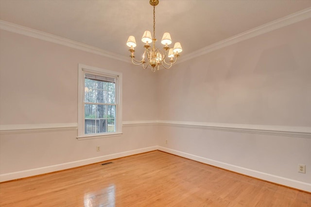 empty room featuring visible vents, baseboards, a chandelier, ornamental molding, and wood finished floors