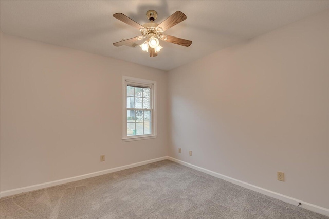 spare room featuring a ceiling fan, light colored carpet, and baseboards