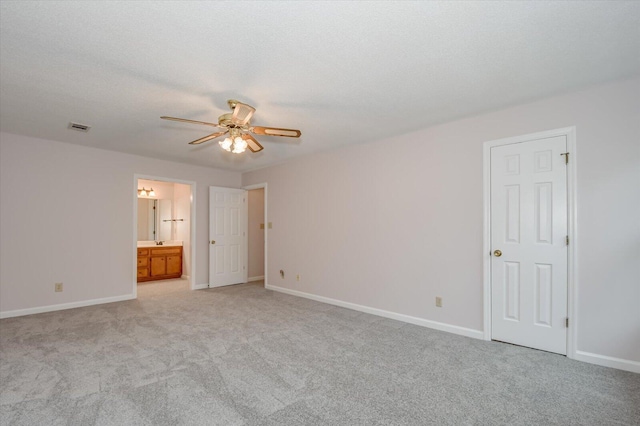 unfurnished bedroom with visible vents, baseboards, light colored carpet, and ensuite bathroom