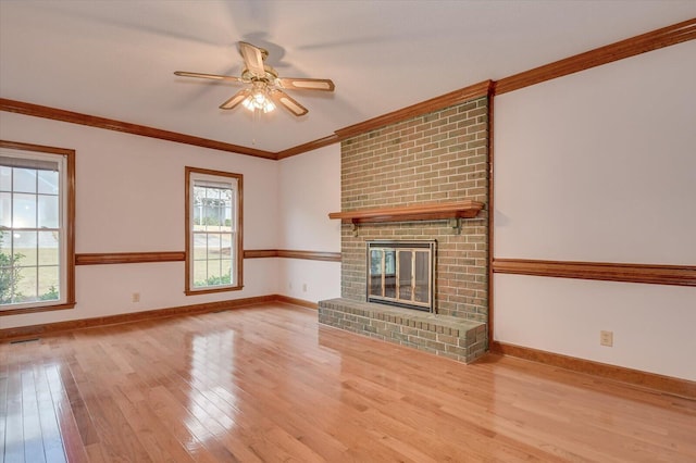 unfurnished living room with ornamental molding, a fireplace, baseboards, and wood finished floors