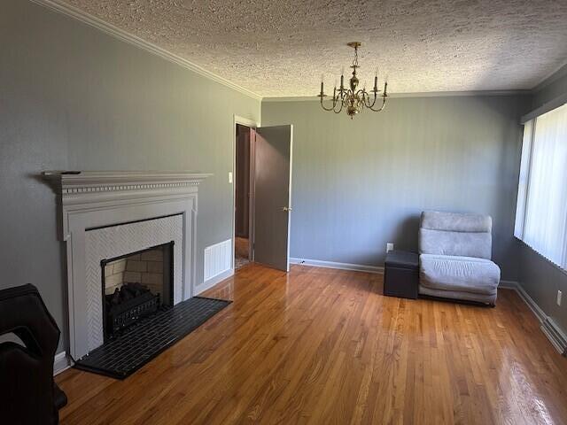 unfurnished room with crown molding, wood-type flooring, a textured ceiling, and a notable chandelier